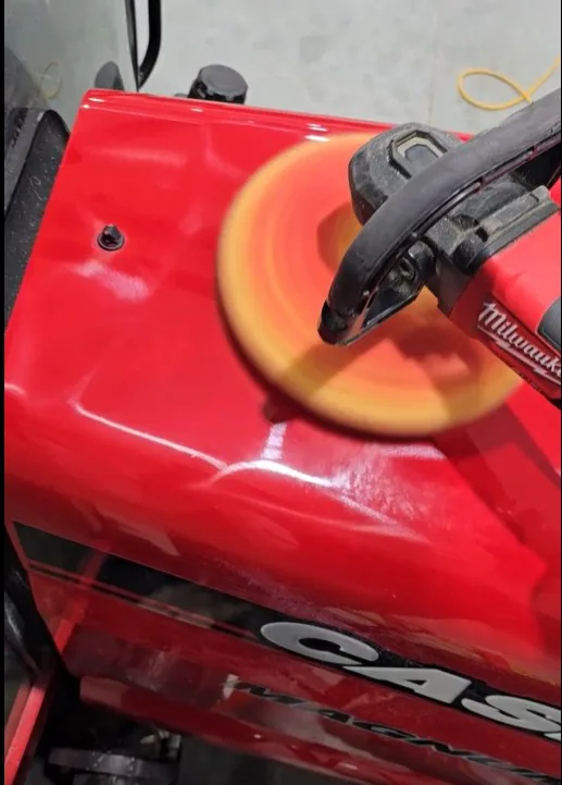 Machine compounding process on red tractor hood